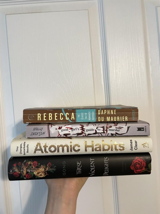 Pictured are the following books: Rebecca, A Good Girls Guide to Murder, Atomic Habits, and These Violent Delights. 